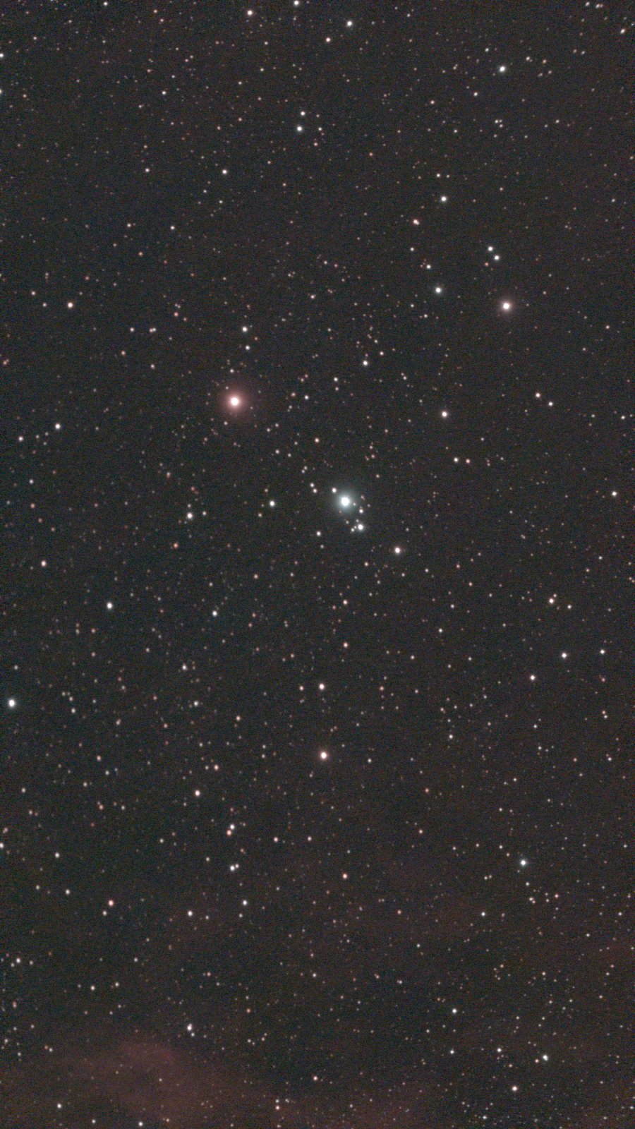 A star field in Cepheus, with faint red nebula at the bottom edge